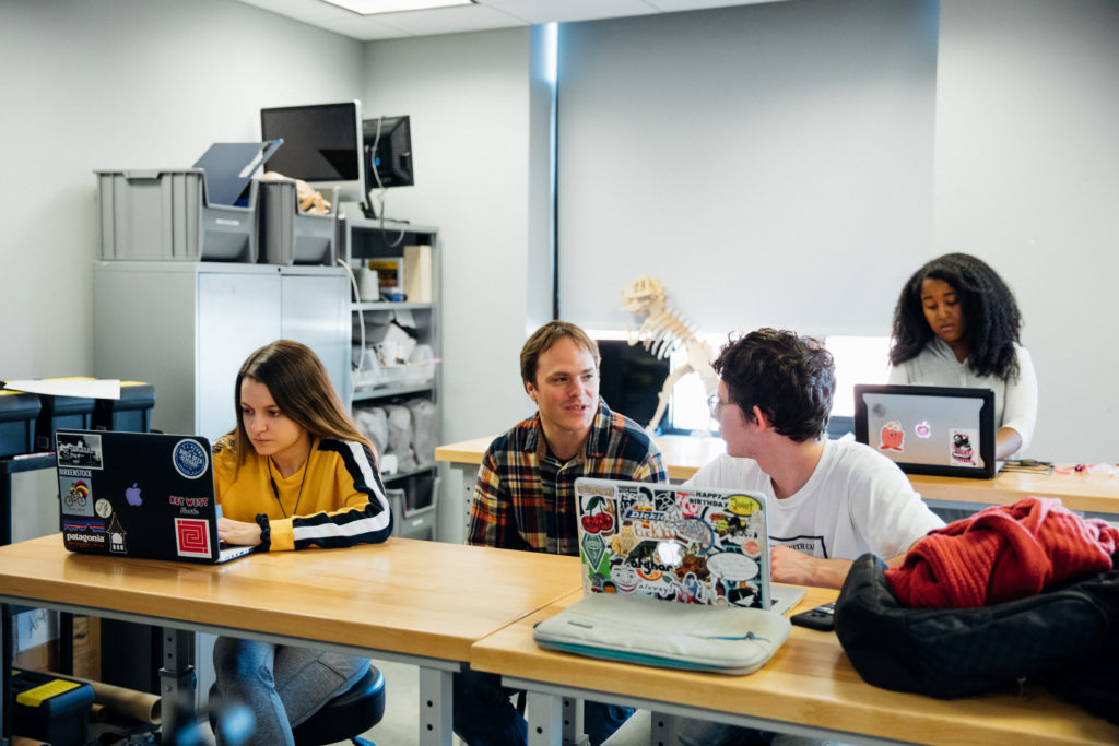 small class of students with laptops talking